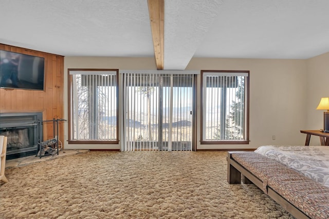 39090 Woodland Rd, Shaver Lake, CA 93664 - carpeted bedroom featuring wooden walls, a glass covered fireplace, and beamed ceiling