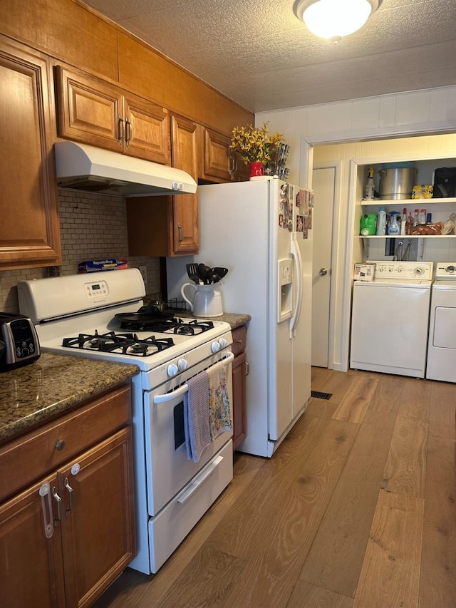 7676 N Fresno St Unit Sp 20, Fresno, CA 93720 - kitchen with white appliances, under cabinet range hood, washer and dryer, light wood-style flooring, and brown cabinetry