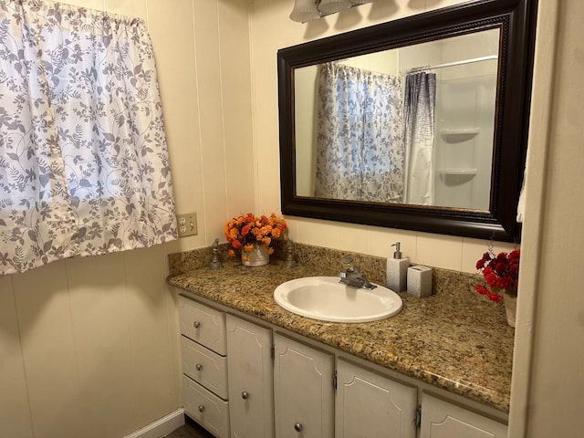 bathroom featuring vanity, a shower with shower curtain, and a decorative wall