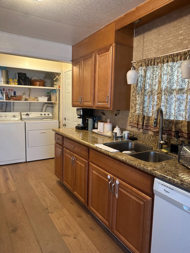 kitchen with a sink, brown cabinetry, independent washer and dryer, dishwasher, and light wood finished floors