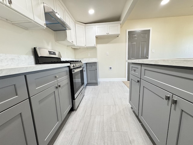 kitchen featuring stainless steel gas range, extractor fan, and gray cabinetry