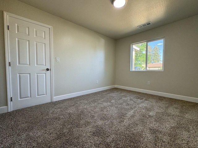 spare room featuring baseboards, visible vents, and carpet