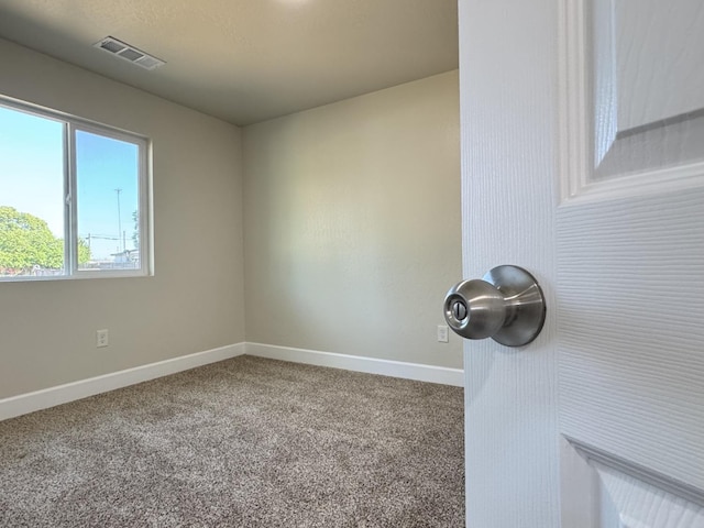 carpeted spare room with visible vents and baseboards