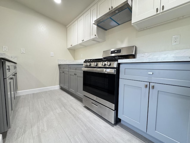 kitchen featuring light wood-type flooring, gas range, baseboards, exhaust hood, and gray cabinetry