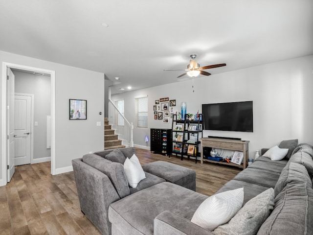 living room featuring stairway, baseboards, a ceiling fan, and light wood-style floors
