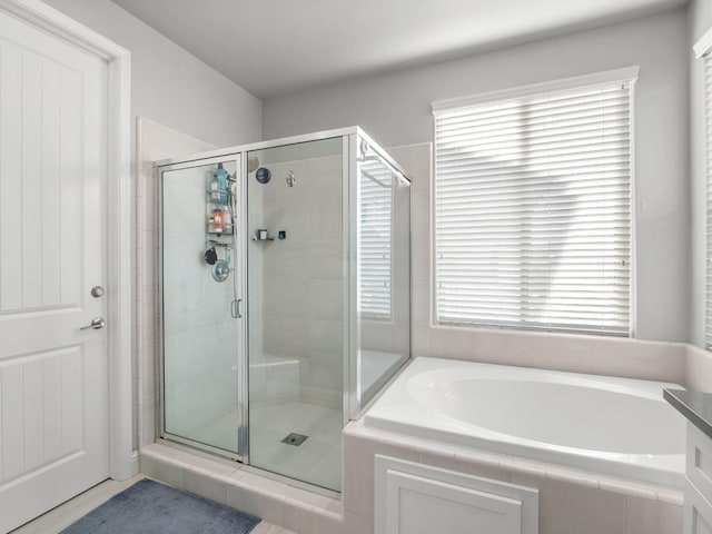 bathroom featuring a shower stall, a healthy amount of sunlight, and a garden tub