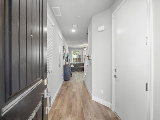 corridor with light wood-style floors, visible vents, baseboards, and recessed lighting