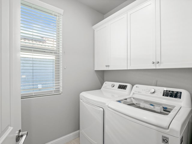 clothes washing area with a wealth of natural light, cabinet space, baseboards, and washer and dryer