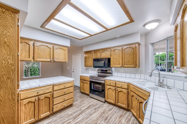 944 N Chapel Hill Ave, Clovis, CA 93611 - kitchen featuring tile countertops, light wood finished floors, a sink, black microwave, and stainless steel range with electric stovetop