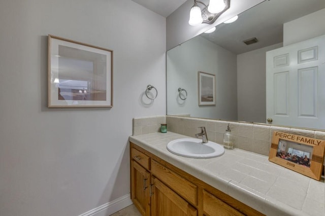 bathroom with vanity, backsplash, baseboards, and visible vents