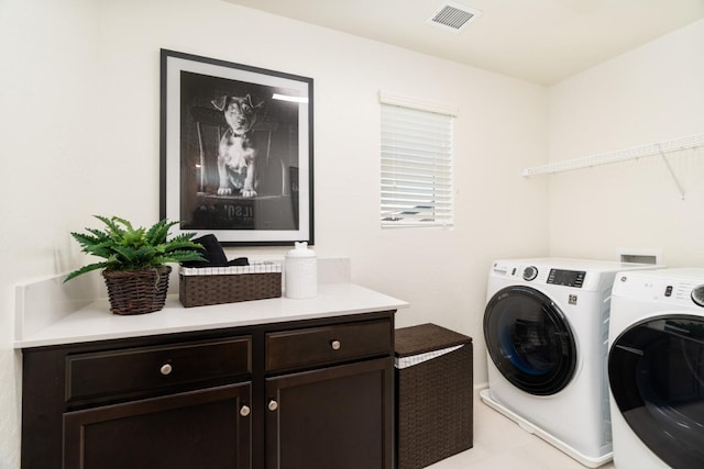 washroom featuring washer and clothes dryer, cabinet space, and visible vents