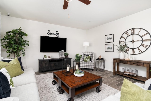 living room featuring a ceiling fan, baseboards, and wood finished floors