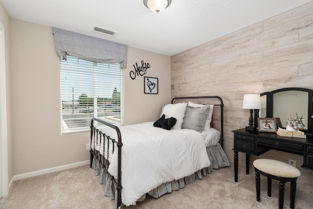 bedroom with carpet flooring, visible vents, wood walls, and baseboards