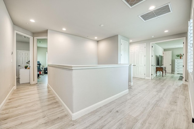 corridor featuring light wood-style flooring, baseboards, and visible vents