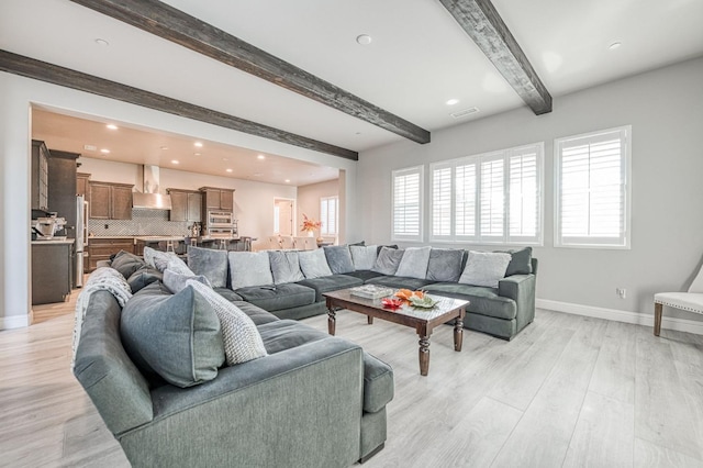 living area with light wood finished floors, beamed ceiling, baseboards, and recessed lighting