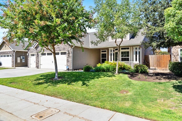 view of front of property with stone siding, a garage, fence, a front lawn, and driveway