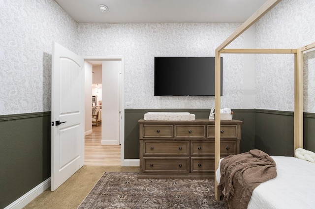 bedroom with baseboards, wallpapered walls, and light colored carpet
