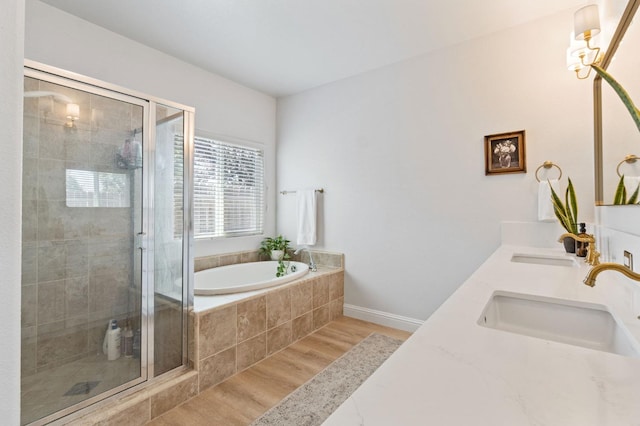 full bath with a garden tub, wood finished floors, a stall shower, and a sink