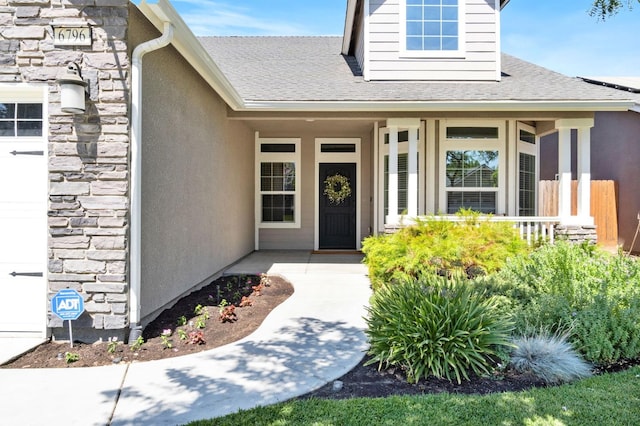 entrance to property with a porch, roof with shingles, stucco siding, and stone siding