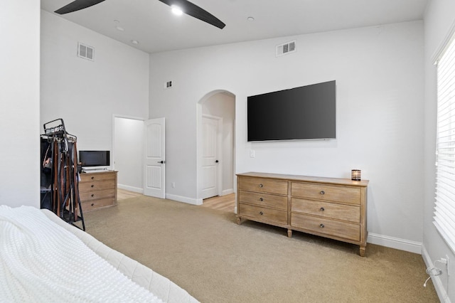 bedroom featuring light colored carpet, visible vents, baseboards, and arched walkways