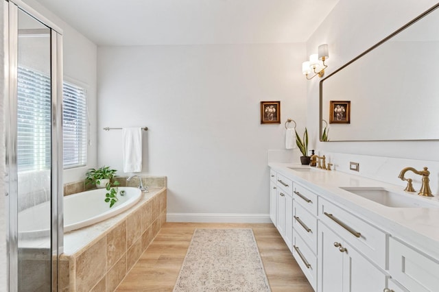 full bath featuring double vanity, a bath, a stall shower, and a sink