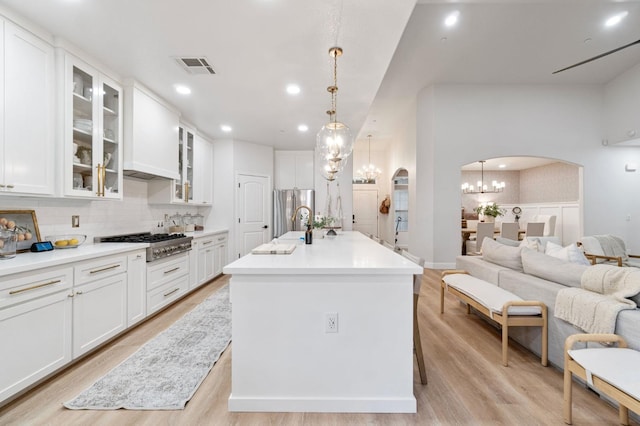 kitchen featuring stainless steel appliances, visible vents, arched walkways, backsplash, and light wood-style floors