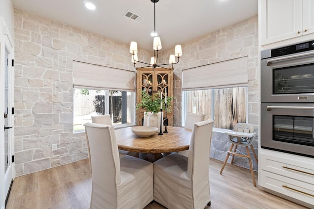dining room with an inviting chandelier, light wood-style floors, and visible vents