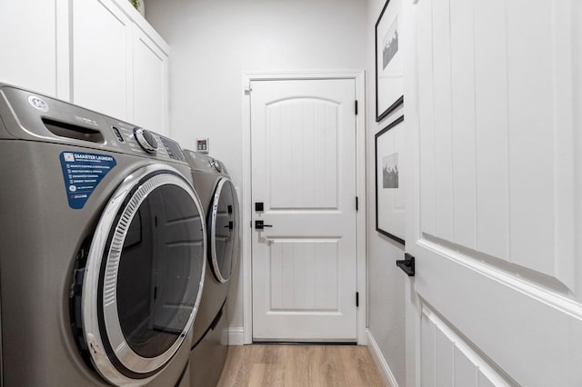 laundry room with washer and clothes dryer, light wood finished floors, cabinet space, and baseboards