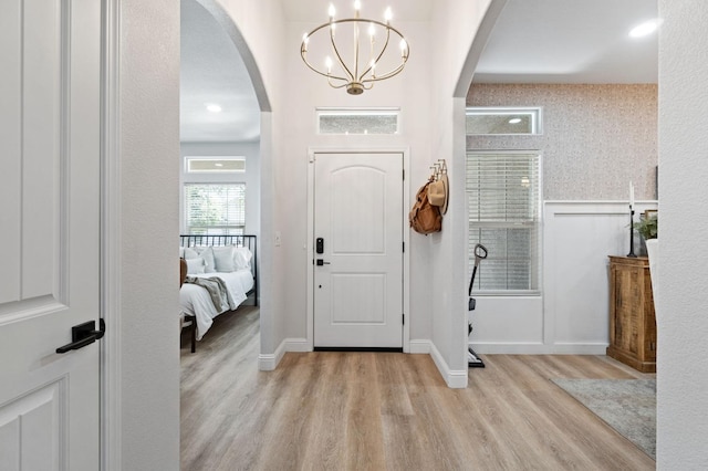 entryway featuring an inviting chandelier, light wood-style flooring, arched walkways, and visible vents
