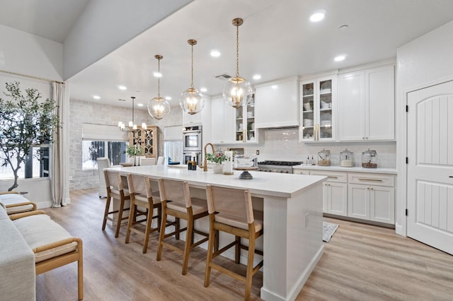 kitchen featuring white cabinetry, light countertops, tasteful backsplash, and a kitchen island with sink
