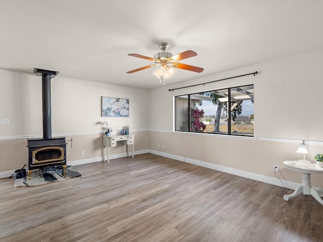 17324 Bonita Rd, Madera, CA 93636 - living room featuring a ceiling fan, a wood stove, baseboards, and wood finished floors
