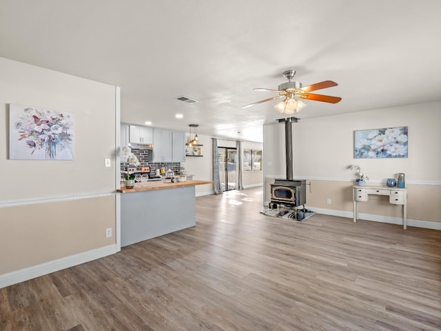 17324 Bonita Rd, Madera, CA 93636 - living room with a wood stove, visible vents, light wood finished floors, and a ceiling fan