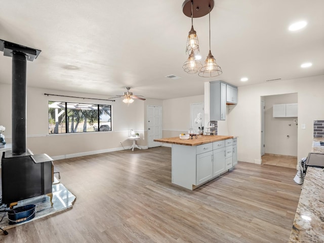 17324 Bonita Rd, Madera, CA 93636 - kitchen with ceiling fan, a wood stove, butcher block counters, and light wood-type flooring