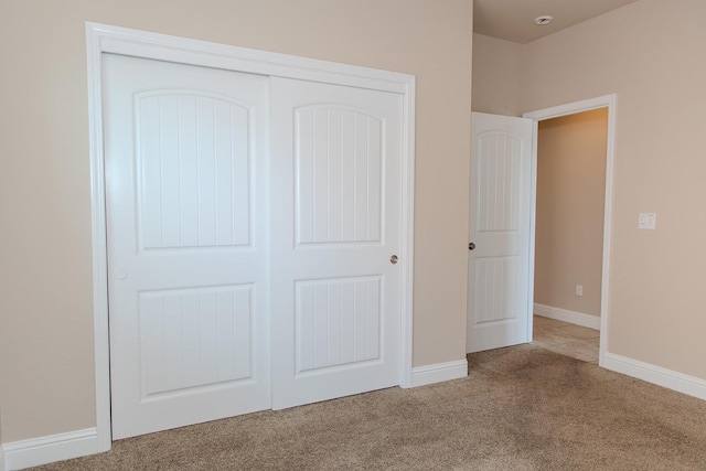 unfurnished bedroom with carpet floors, a closet, and baseboards