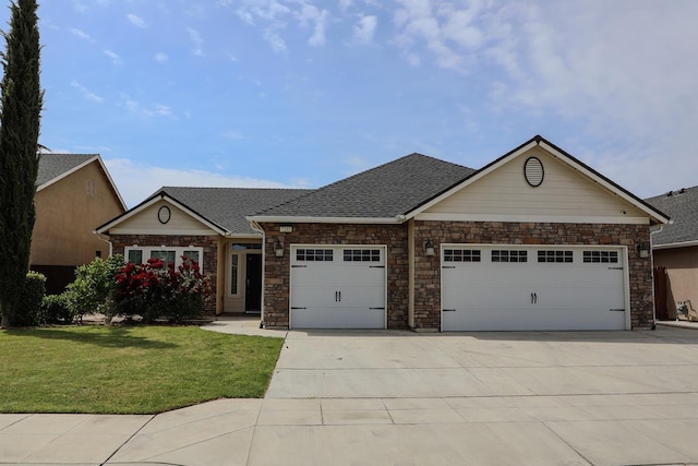 view of front facade with an attached garage, stone siding, concrete driveway, a front yard, and a shingled roof
