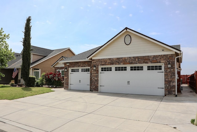 view of front of house featuring fence, stone siding, driveway, a garage, and a front yard