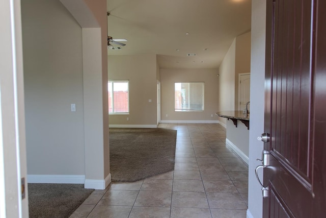 foyer with light tile patterned floors, visible vents, baseboards, and a ceiling fan