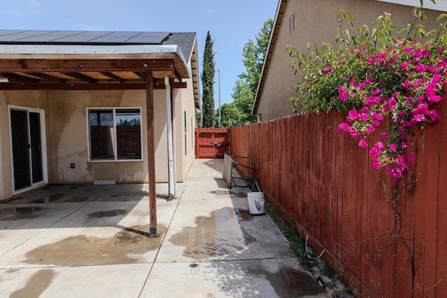 view of home's exterior featuring solar panels, stucco siding, a fenced backyard, and a patio area
