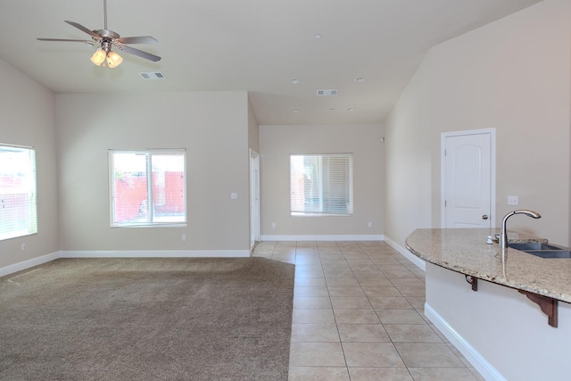 unfurnished living room featuring light tile patterned floors, a wealth of natural light, visible vents, and a sink