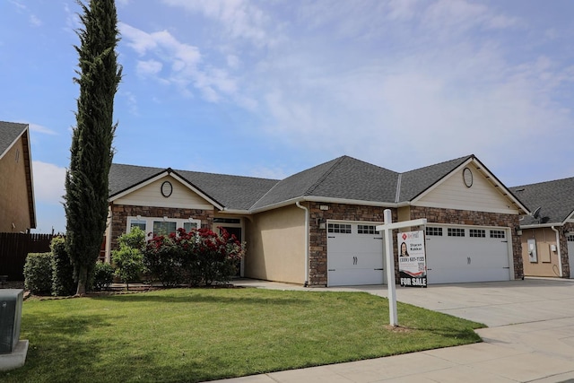 view of front of property with an attached garage, stone siding, driveway, a front yard, and a shingled roof