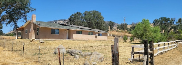 exterior space with roof mounted solar panels, fence, stucco siding, and a chimney