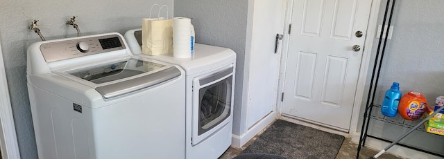 clothes washing area featuring separate washer and dryer, laundry area, and a textured wall
