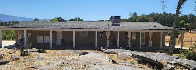 back of house with a mountain view, a patio area, and a chimney