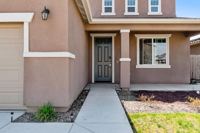 view of exterior entry with stucco siding and covered porch