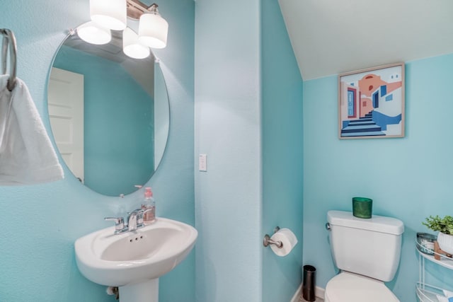 bathroom with toilet, vaulted ceiling, and a sink