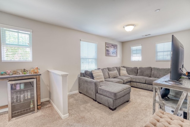 living room featuring wine cooler, baseboards, visible vents, and light colored carpet