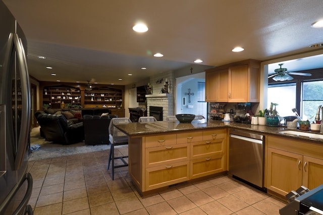 1233 Redwood Ln, Selma, CA 93662 - kitchen featuring appliances with stainless steel finishes, a sink, light tile patterned floors, a peninsula, and dark stone countertops
