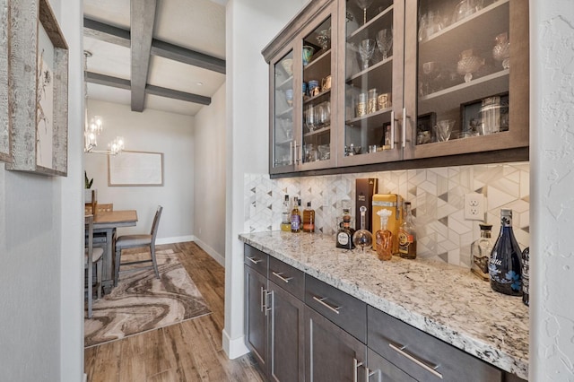 bar area featuring wood finished floors, backsplash, beamed ceiling, baseboards, and coffered ceiling