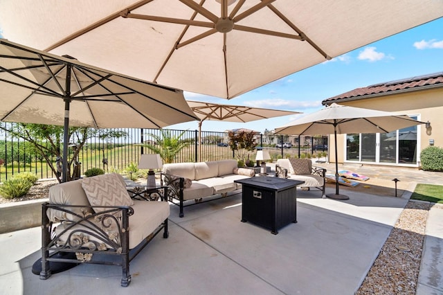 view of patio with an outdoor living space with a fire pit and fence