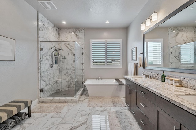 bathroom with marble finish floors, a freestanding tub, a shower stall, double vanity, and recessed lighting